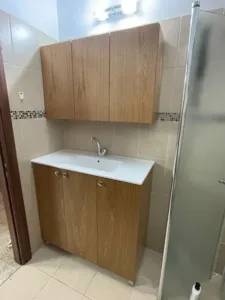 ארון אמבטיה קטן צדדי בצבע חום עם ארון מתחת לכיור ומעל הכיור