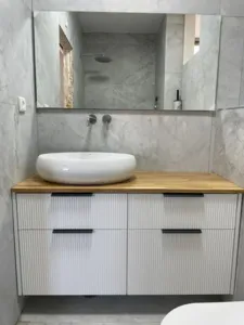 ארון אמבטיה עם קירות שיש בצבע אפור כיור בצבע לבן ומראה לאורך כל הקיר