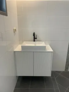 ארון אמבטיה קטן לבן עם פסים קירות לבנות וברז שחור