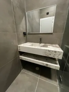 ארון אמבטיה משיש לבן וגוונים חומים מופרד לשניים אם פתיחה באמצע ומראה מרובעת