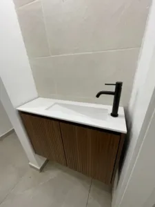 ארון אמבטיה פינתי בצבע חום עם ידיות מובנות בפנים כיור לבן וברז שחור