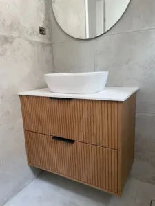 ארון אמבטיה בצבע חום עץ עם פסים וידיות בצבע שחור וכיור לבן