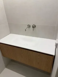 ארון אמבטיה בצבע חום עץ וברז כסף מוטמע בקיר