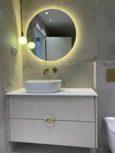 ארון אמבטיה בצבע לבן עם פסים ואור שיורד מהתקרה לגובה המארה העגולה