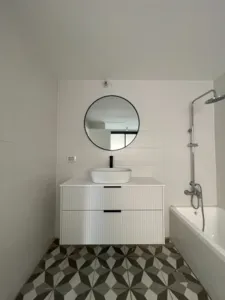 ארון אמבטיה קטן ליד המקלחת ומראה עגולה וקטנה