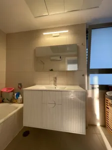 ארון אמבטיה בצבע לבן עם כיור בצבע לבן אמבטיה בצד עם אור למעלה