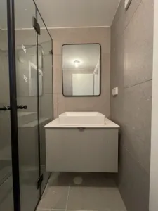 ארון אמבטיה קטן עם כיור מקלחת בצד ומראה עם פס שחור בצד
