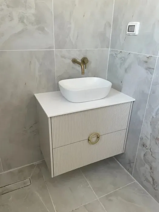 ארון אמבטיה בז עם ברז זהב וקירות אפורים